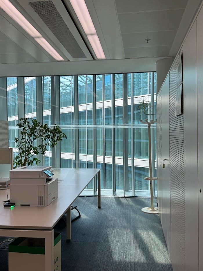 Bright office space in Milano with tech setup, greenery, and architectural design.